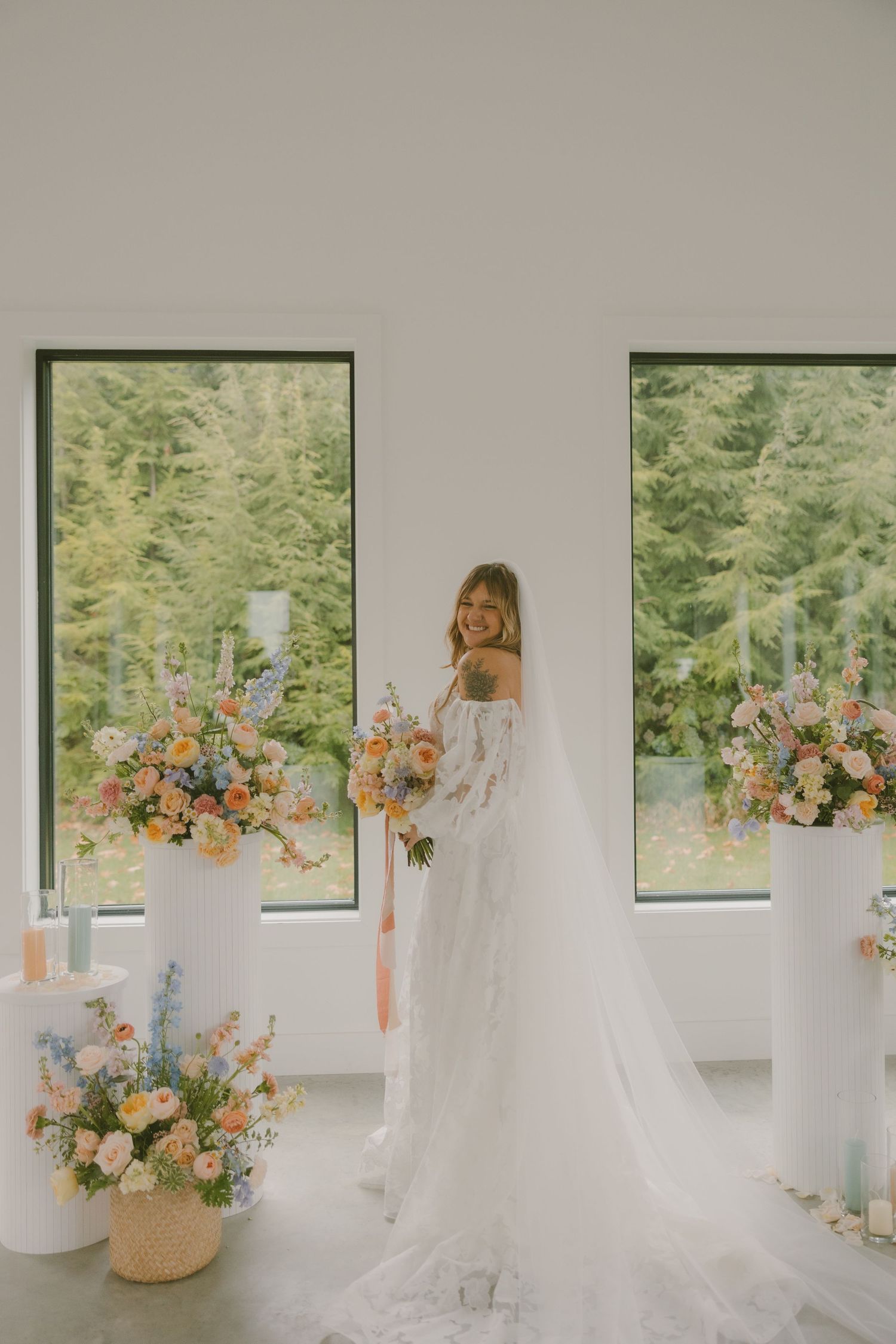 Modern white wedding venue with floor-to-ceiling windows and peach floral arrangements.