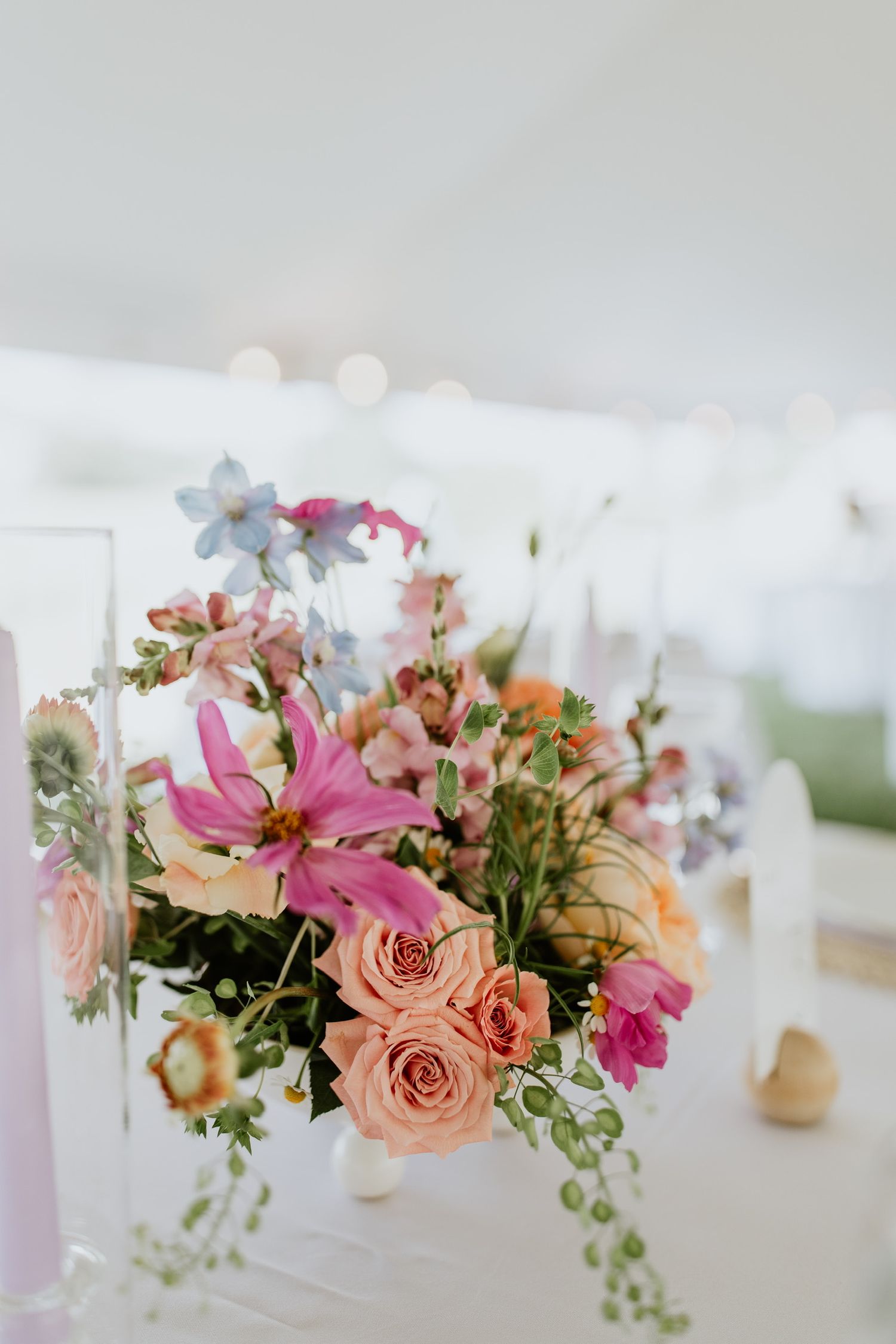 Close-up of pink and peach floral centerpiece with roses and trailing greenery.