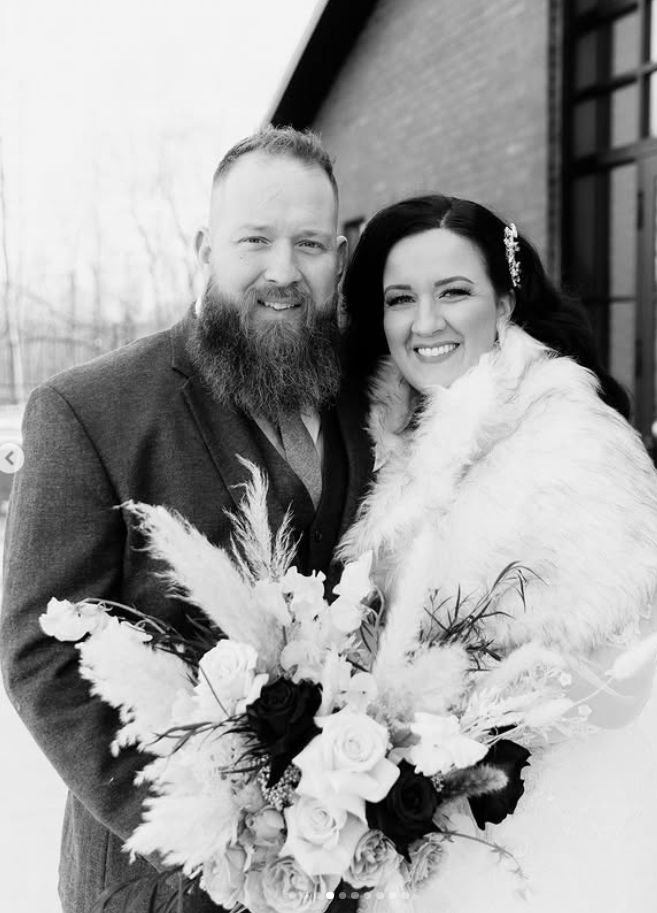 Black and white winter wedding portrait featuring fur wrap and dramatic floral bouquet.