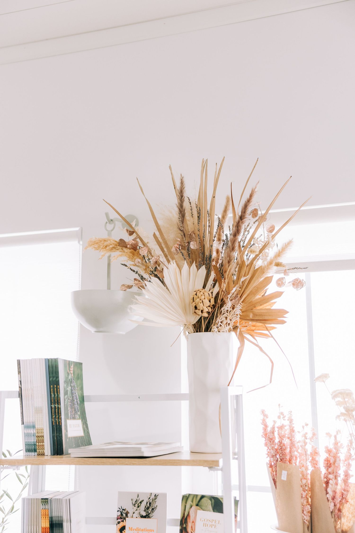 Elegant dried pampas grass and wheat arrangement in white vase on minimalist shelf.