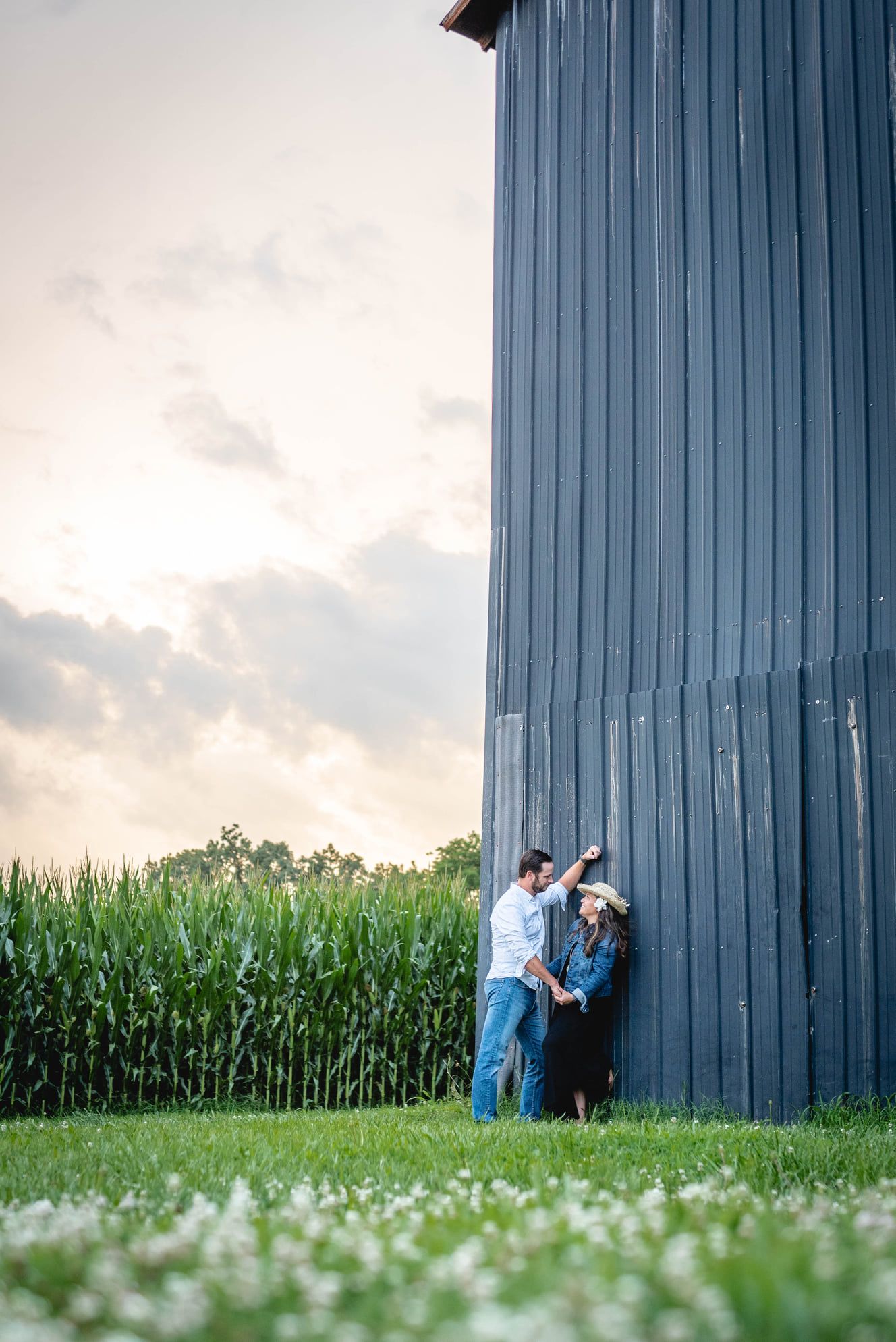 Sexy photo of husband and wife leaning against a barn during a summer family photoshoot in Clarksville, Tennessee or Kentucky