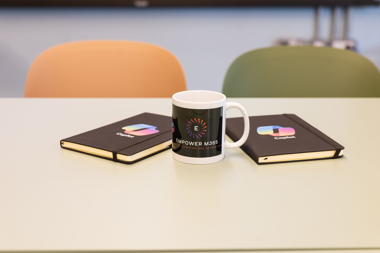 Black Empower Now branded mug flanked by two notebooks with colorful logos on a white table.