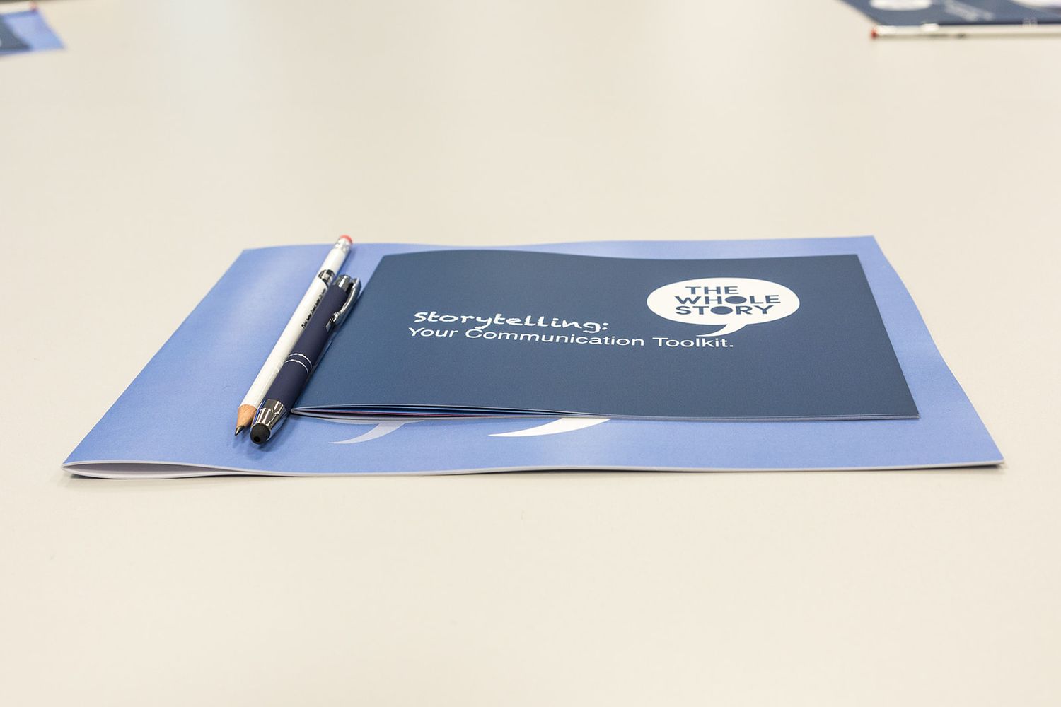 A storytelling communication toolkit booklet with a pen on a conference table.