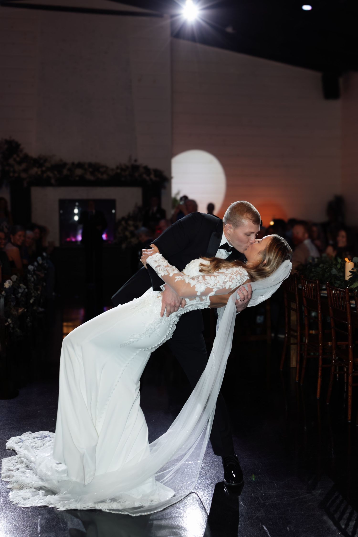 Bride and groom share a romantic dip kiss on the dance floor during their wedding reception.