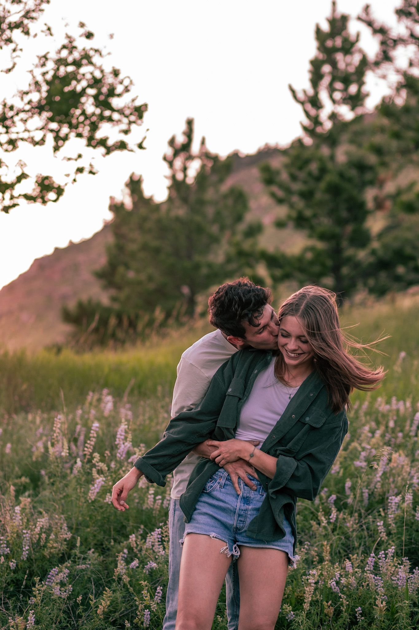 Couple embracing with the mountainous backdrop of Horsetooth Falls in Fort Collins, Colorado.