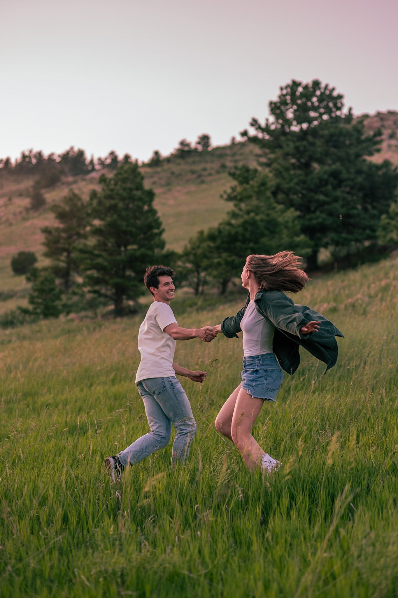 Couple dancing in a field with the mountainous backdrop of Horsetooth Falls in Fort Collins, Colorado.
