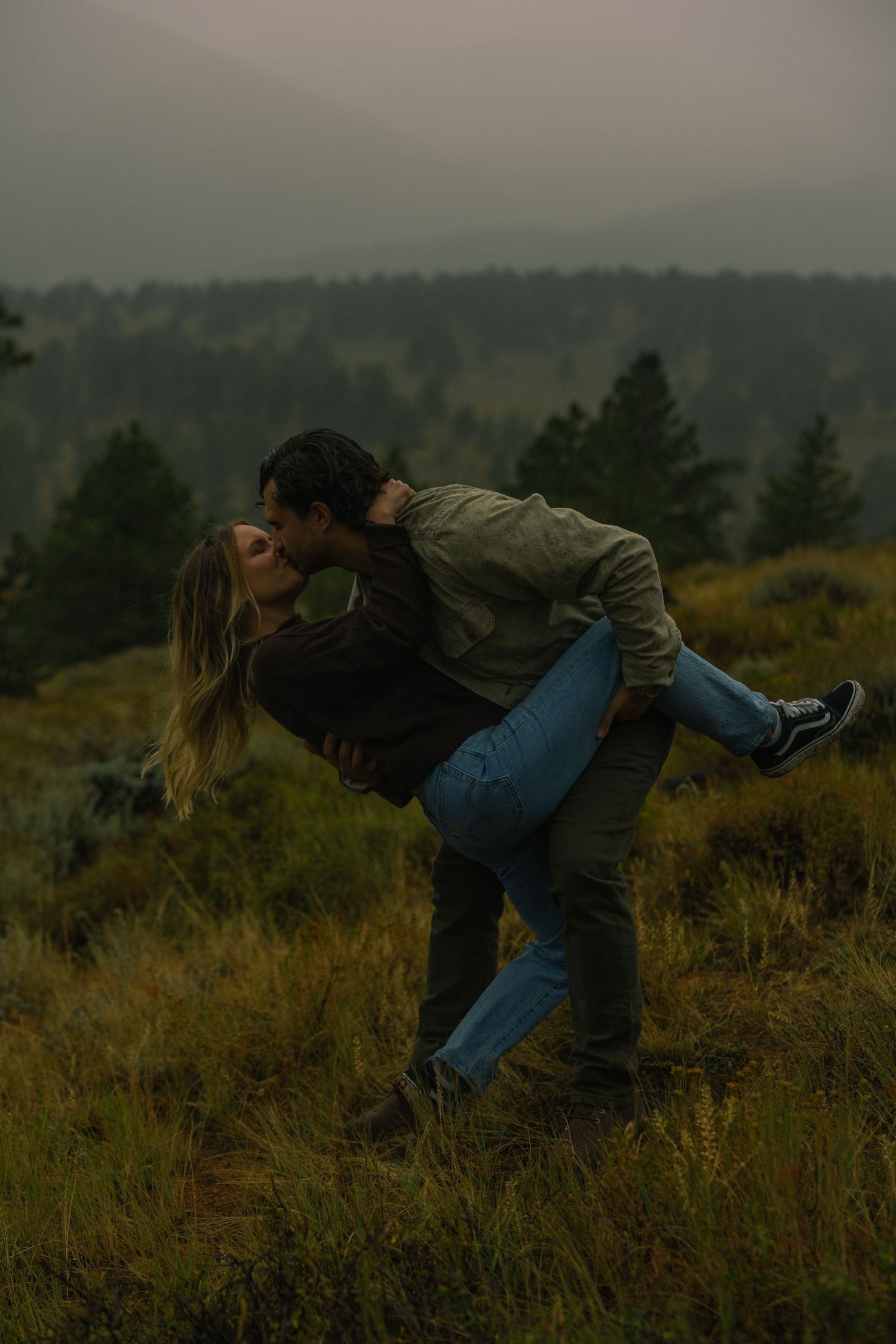 A couple kissing passionately in the rain in the romantic setting of Rocky Mountain National Park, Colorado.