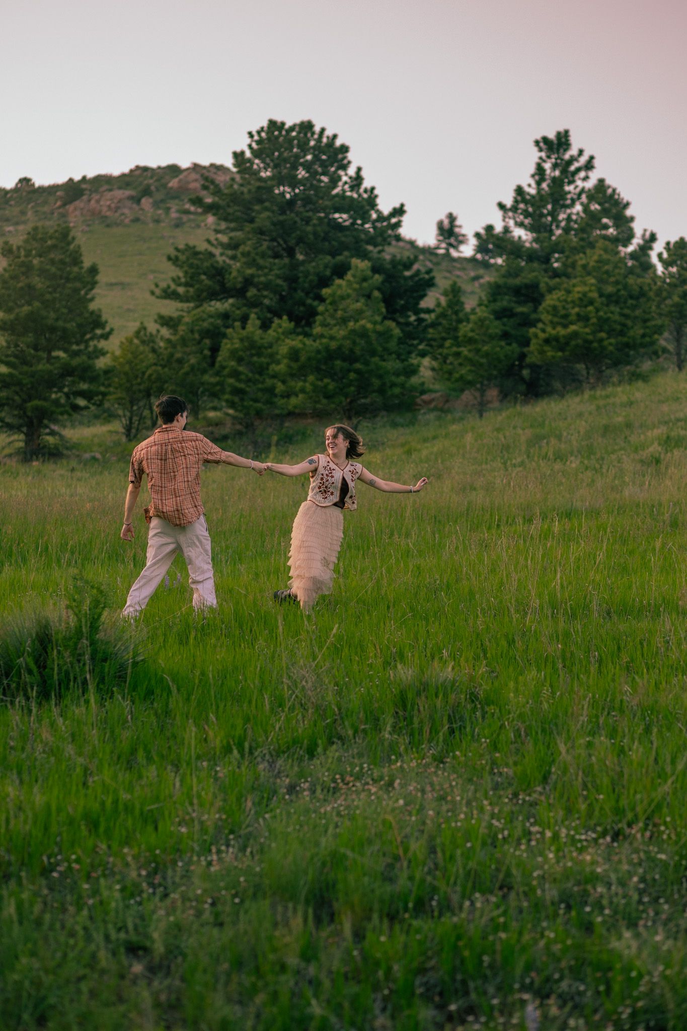 A couple running through the fields with a mountainous backdrop in Fort Collins, Colorado.