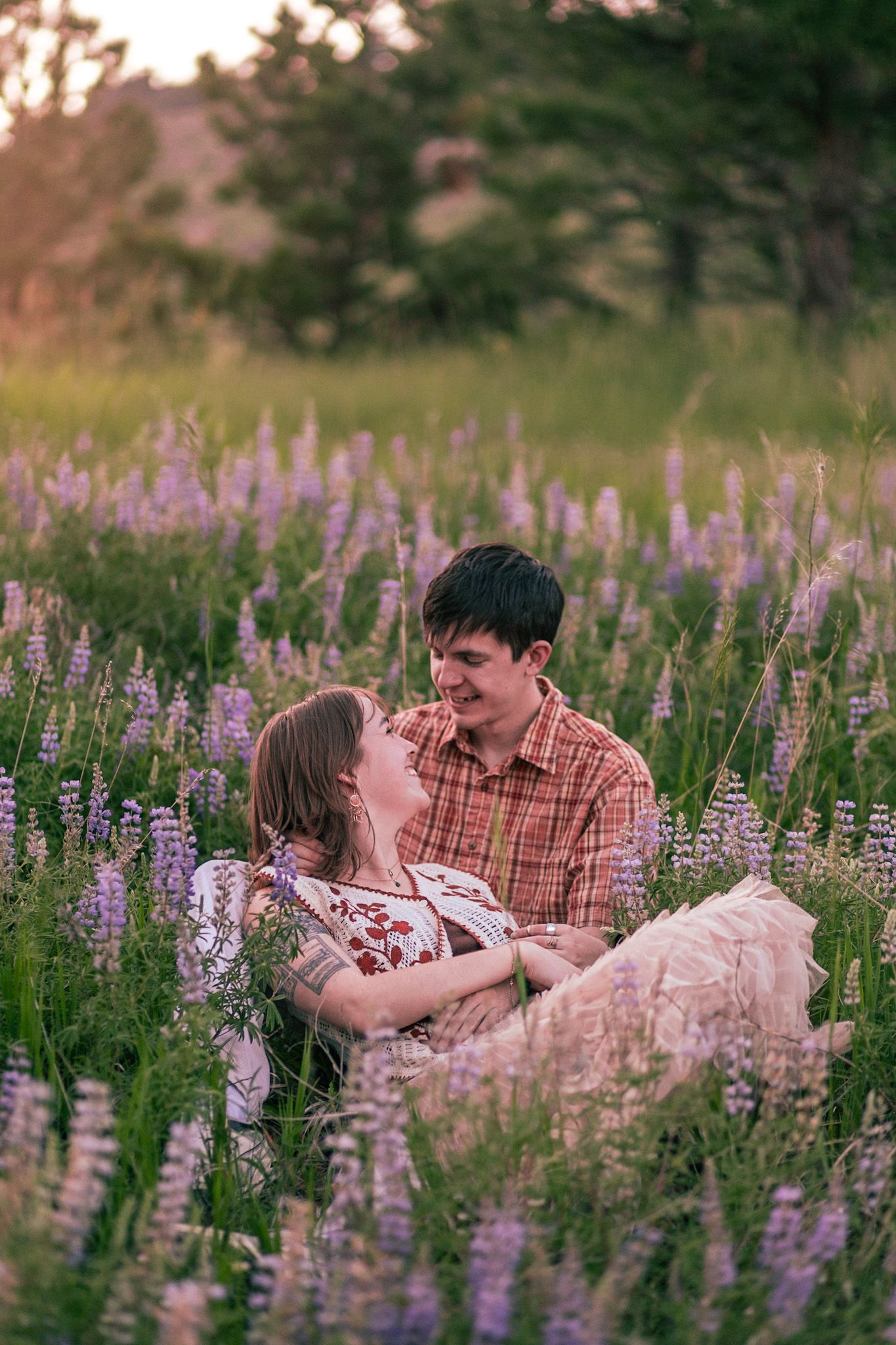 A couple sitting in the wildflowers with a mountainous backdrop in Fort Collins, Colorado.