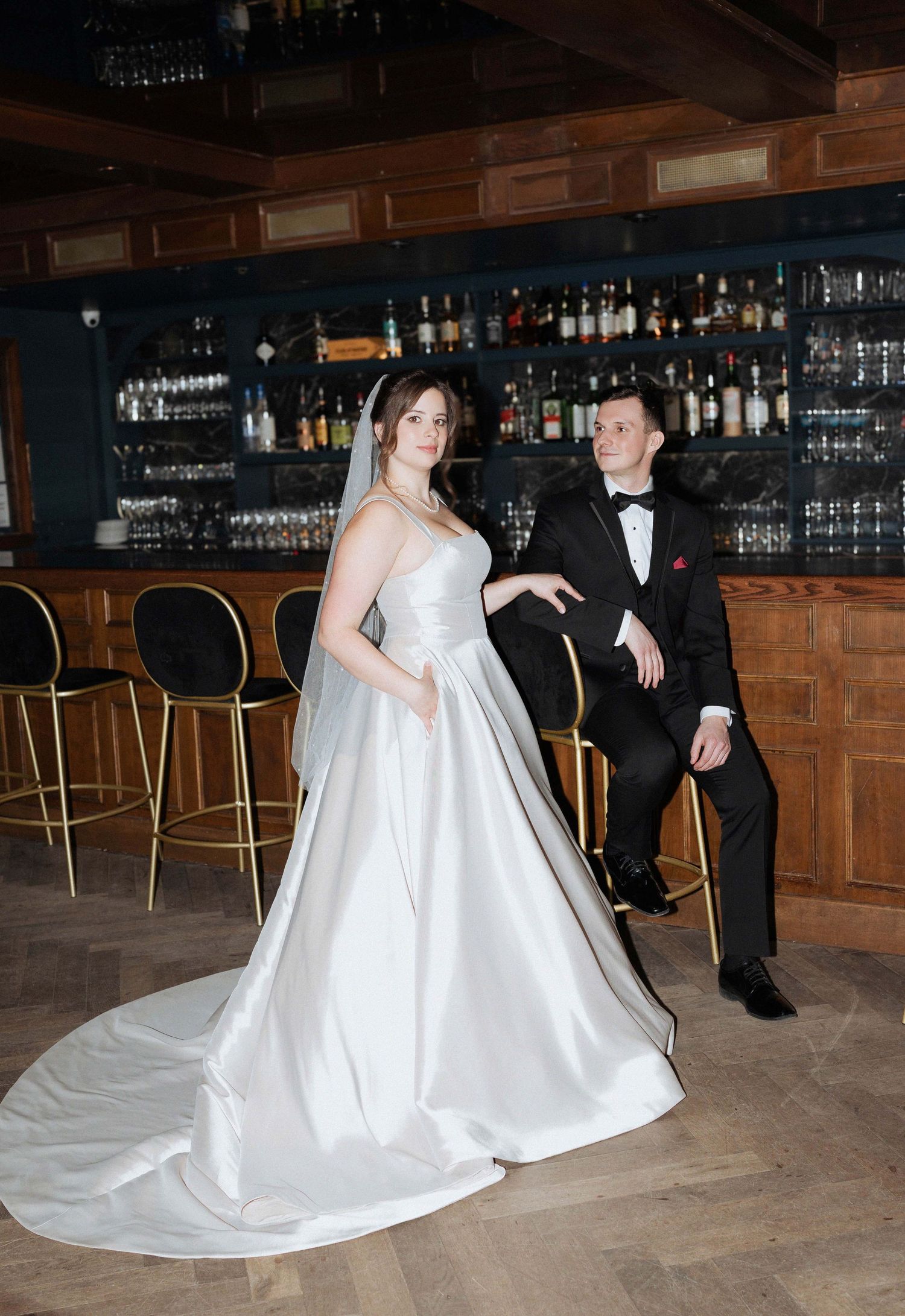 A sequence of dance moves between a couple in formal attire at a bar venue with wood paneling and glassware.