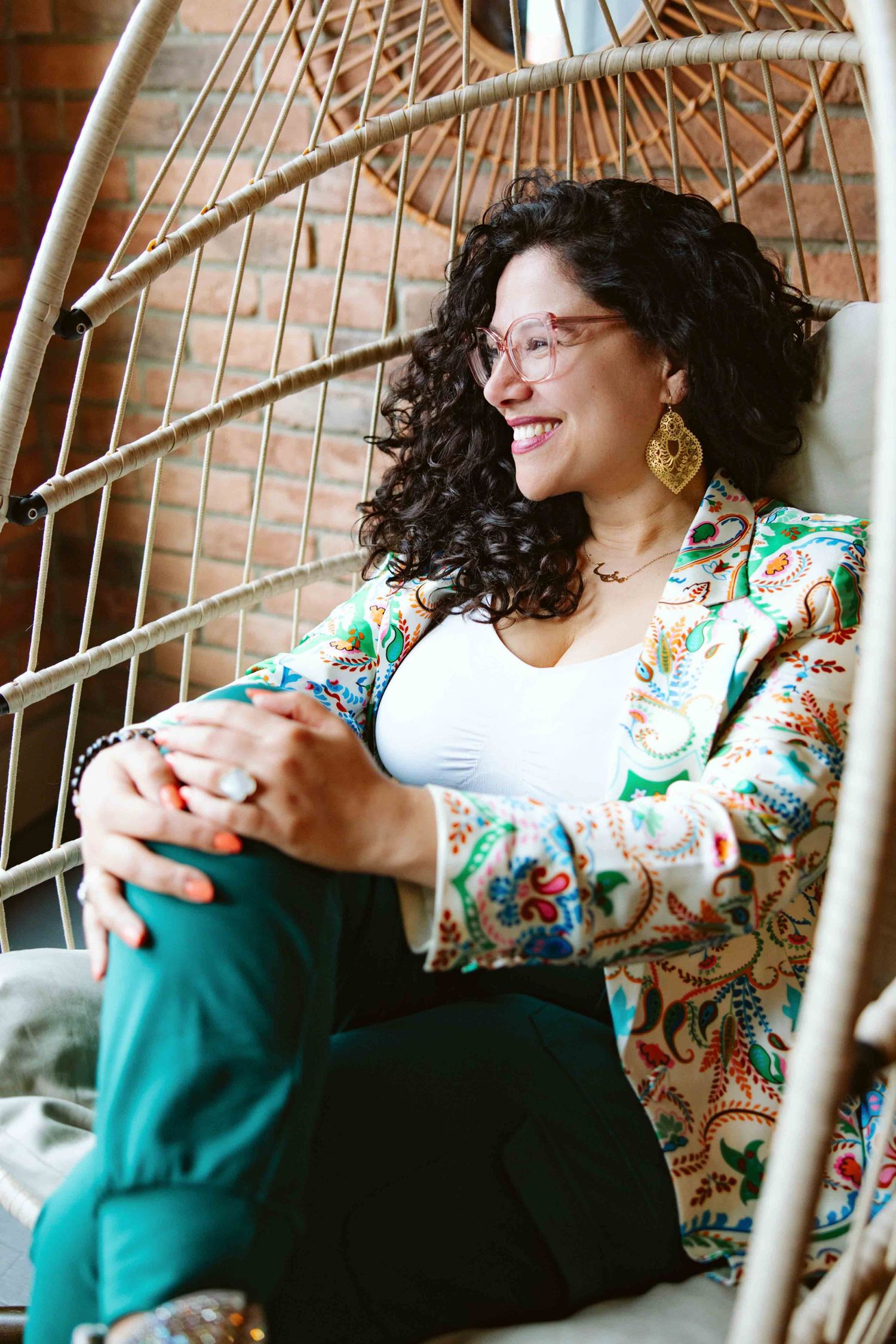 Person in floral print relaxing in wicker chair with natural lighting.