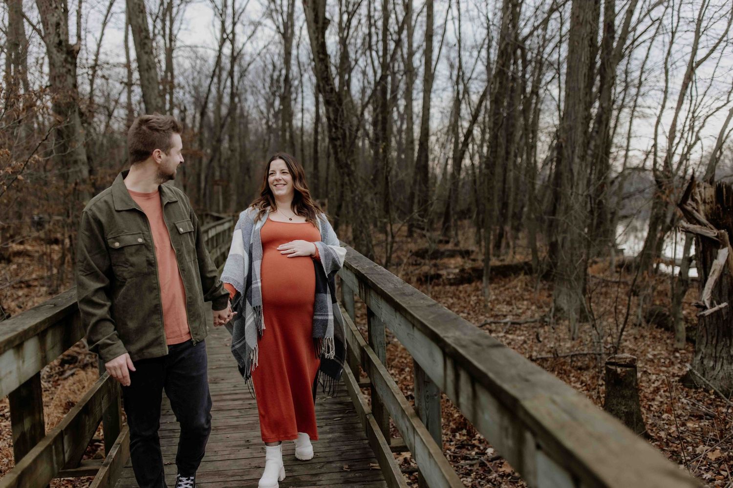 Couple walking together on elevated wooden pathway through autumn woods.