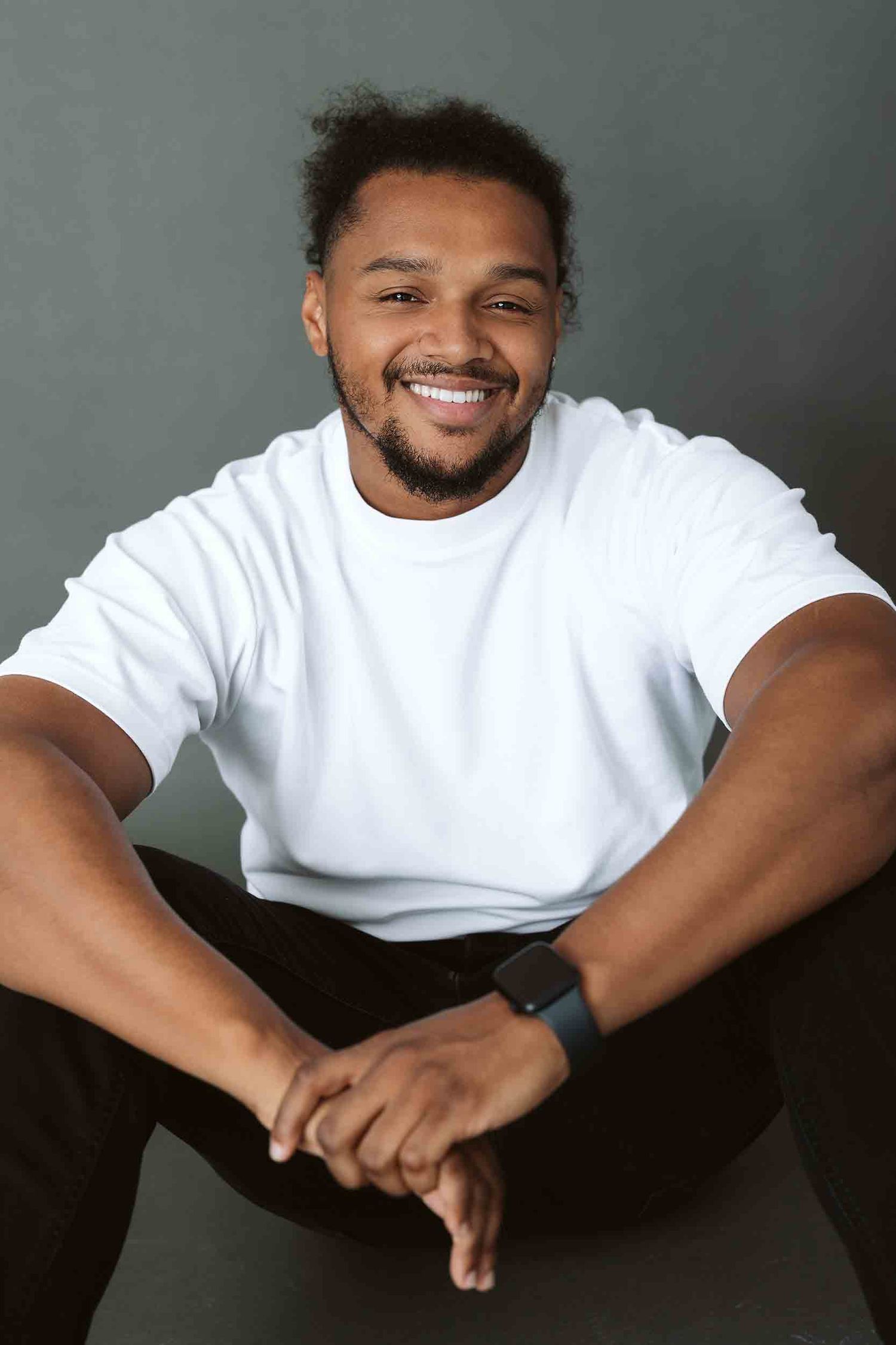 Casual portrait of person in white t-shirt sitting with friendly expression.