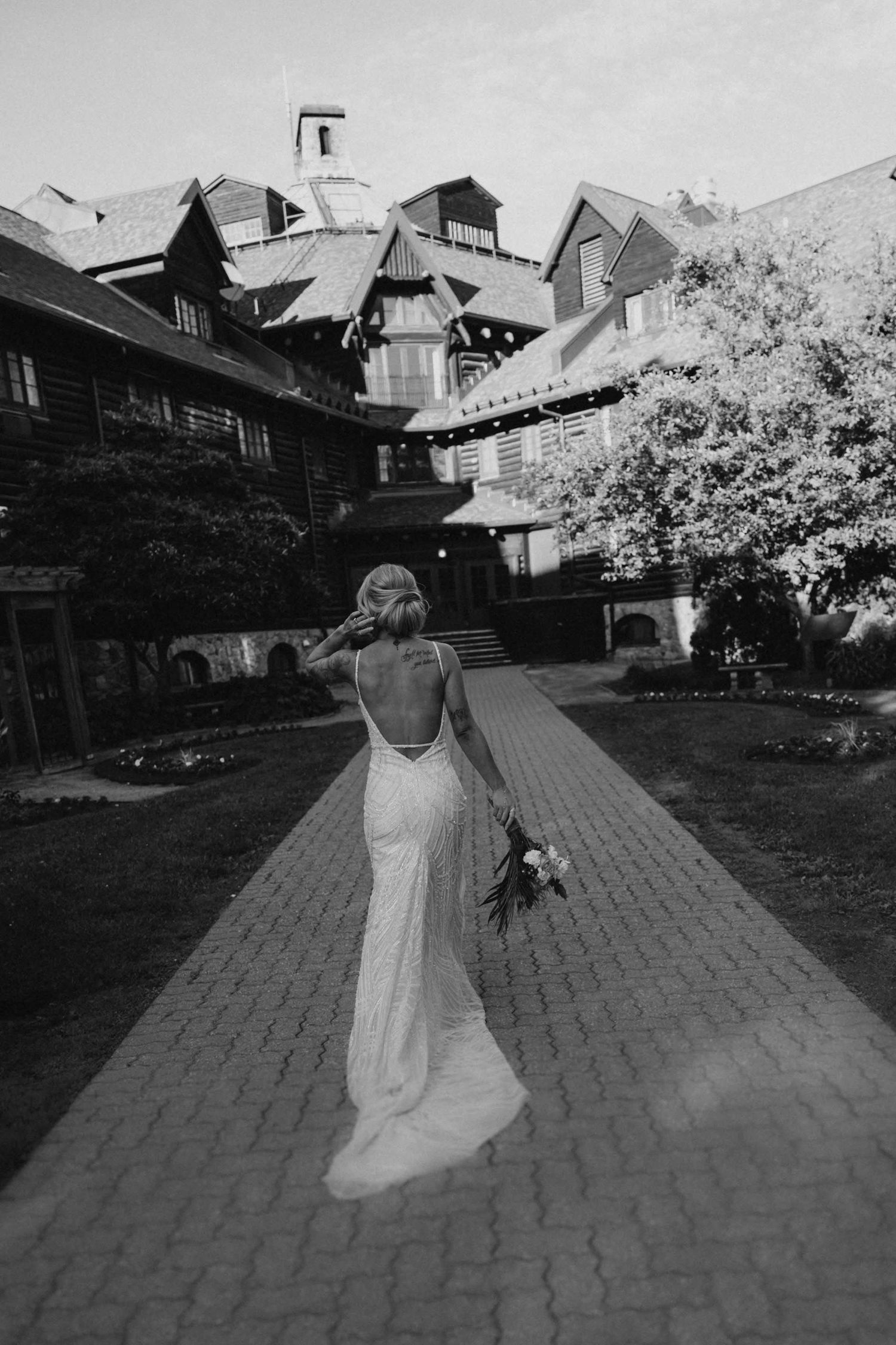Bride walks along brick pathway in flowing white dress.