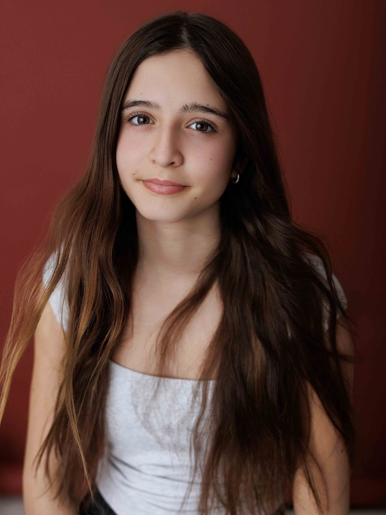 Studio portraits with burgundy background showing natural expressions and long dark hair.