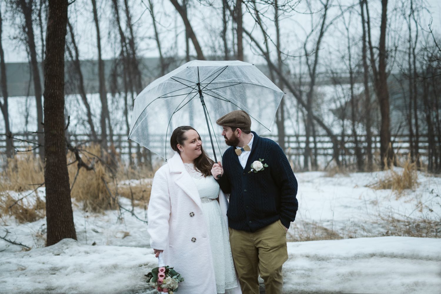 Winter wedding photography session in snowy forest with bare trees.