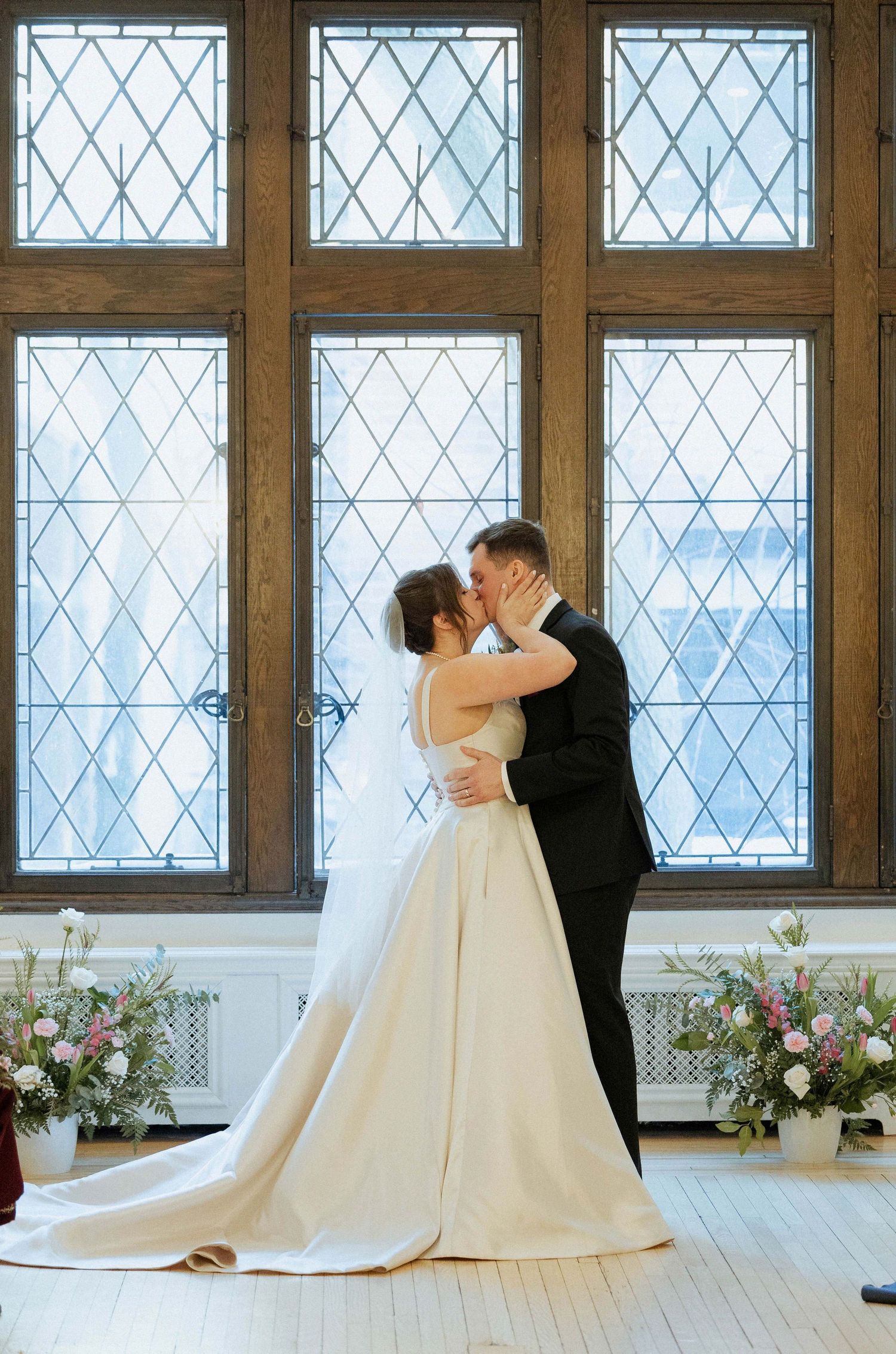A romantic dance sequence in front of diamond-paned windows with natural light streaming through and floral arrangements.