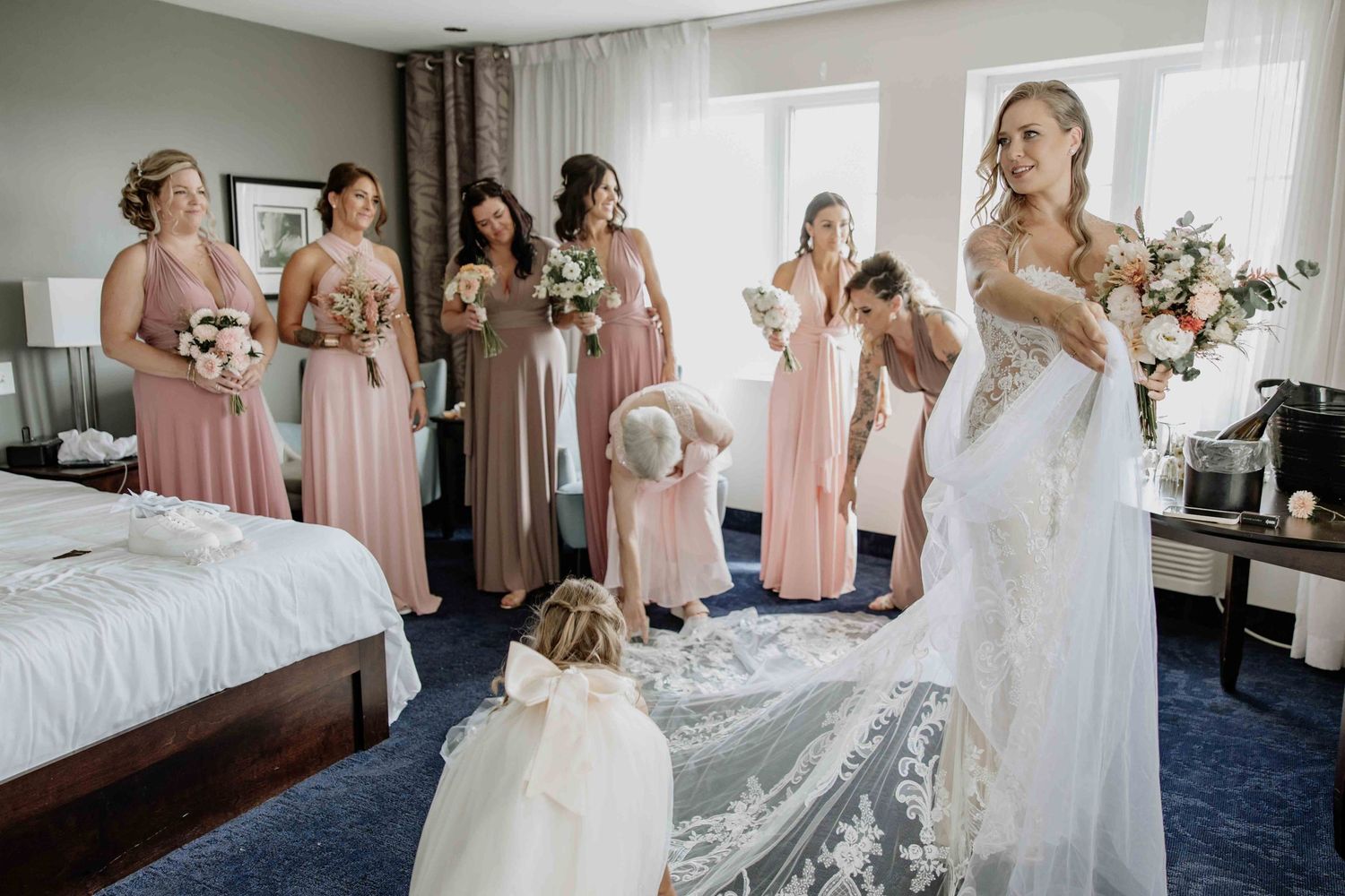 Wedding party preparations in elegant hotel room with bridesmaids in pink dresses.