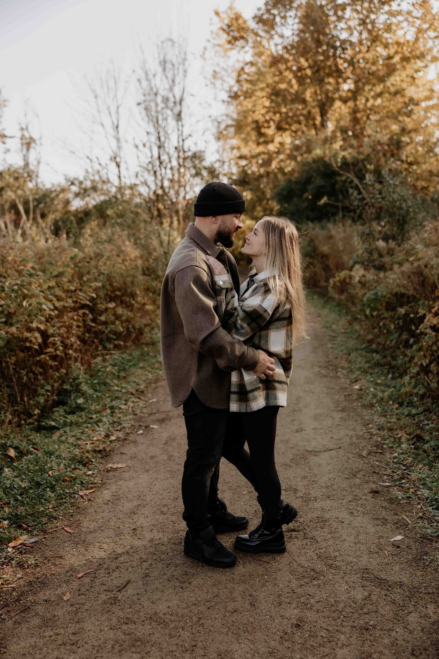 A couple sharing an intimate moment on a dirt path during golden hour.
