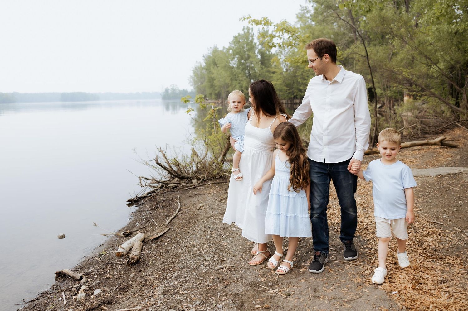Family walking together along a lakeside path during an outdoor photo session.