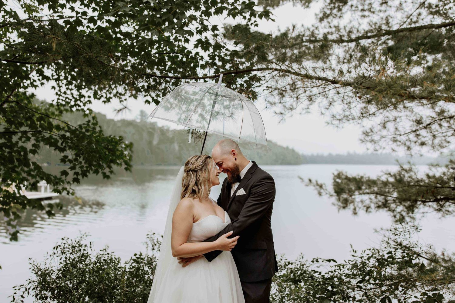 Romantic lakeside wedding portraits with natural scenery and overhanging trees.