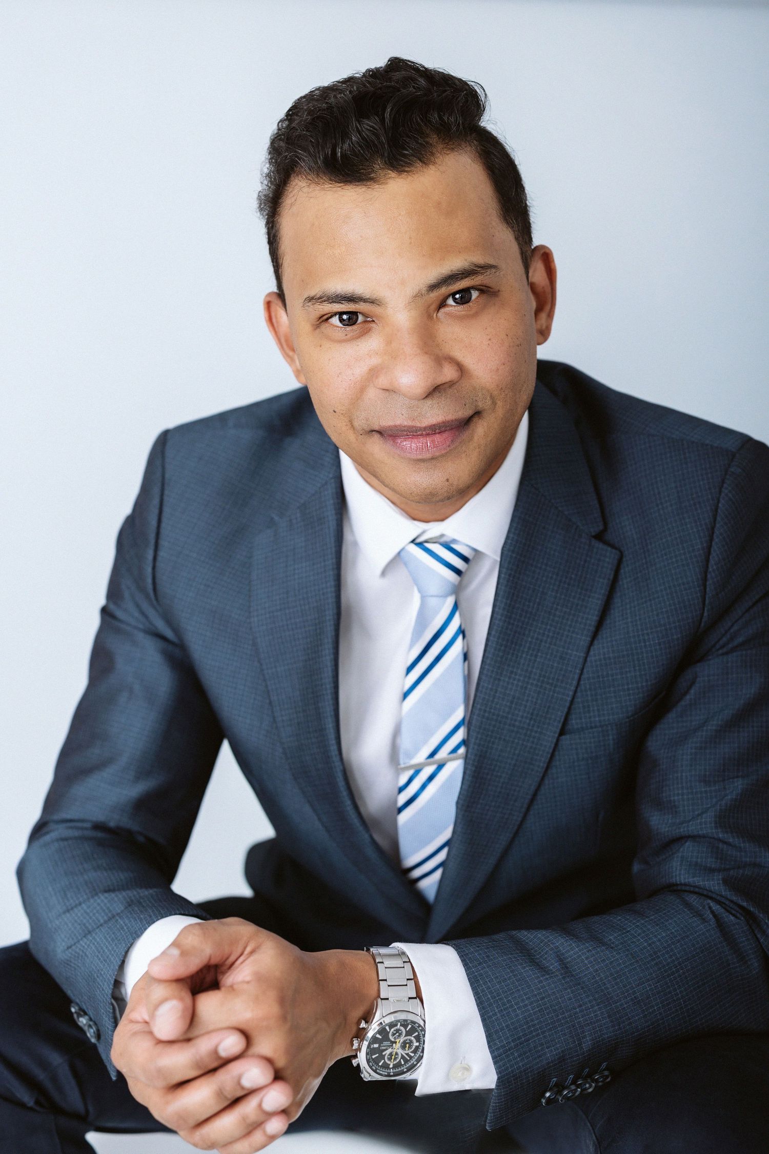 Executive in a navy suit and striped tie poses for a professional headshot.