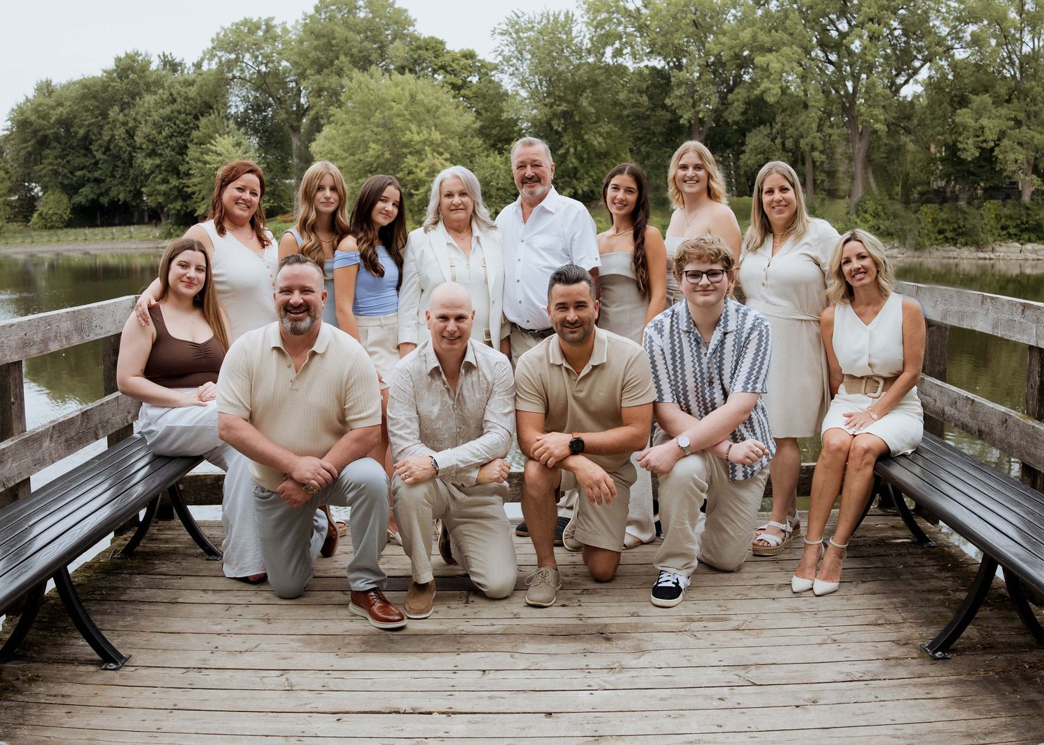 Large family group portrait on a wooden dock by a lake, posing together for a formal outdoor photo.