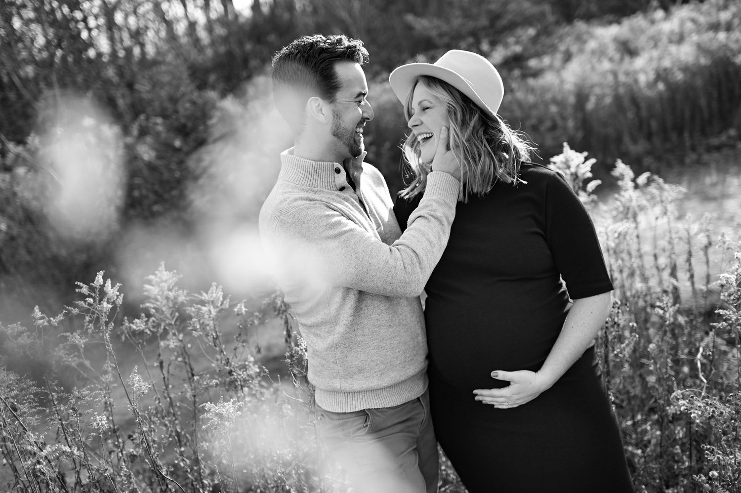 Black and white maternity portraits in outdoor field with natural elements.