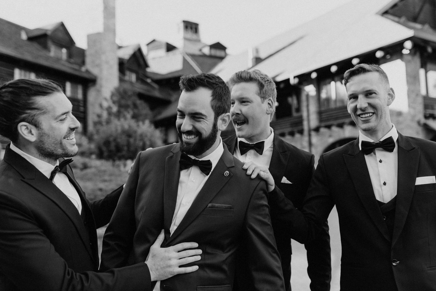 Black and white candid shots of groomsmen sharing laughs in formal attire.