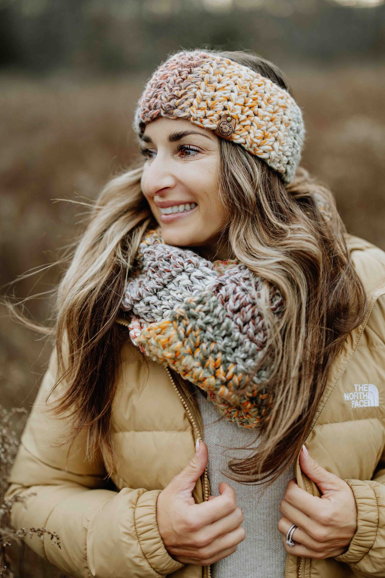 Person wearing knit scarf and beige puffer jacket in outdoor winter setting.