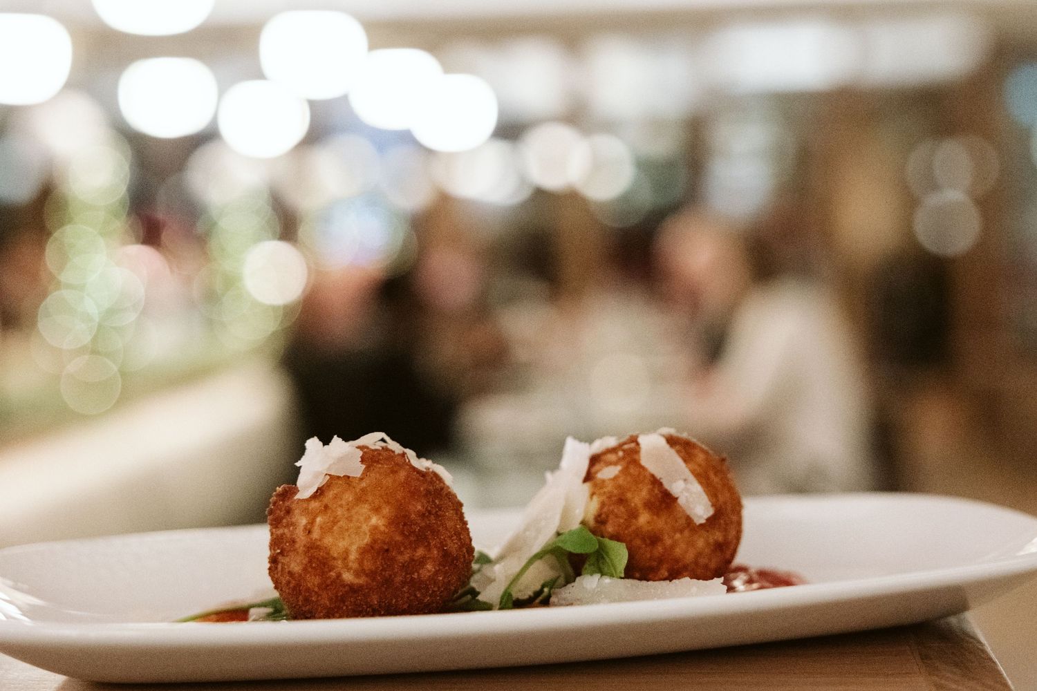 Elegantly plated restaurant dishes with blurred background lighting.