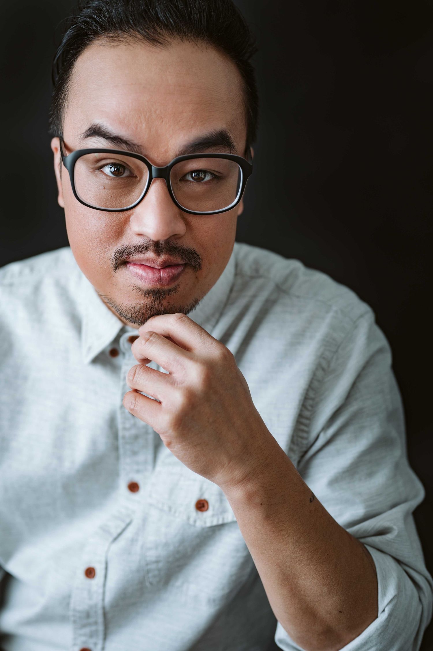 Studio portraits showing different expressions of person in light colored shirt.