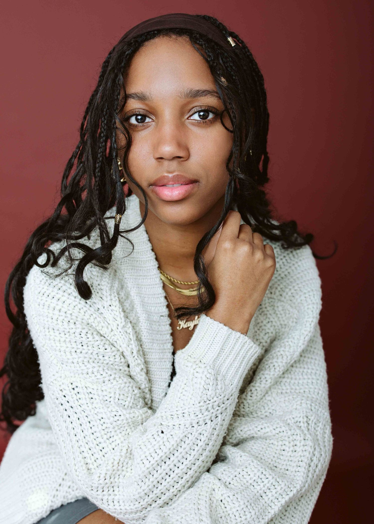 Portrait series showing model in white knit sweater against burgundy background.