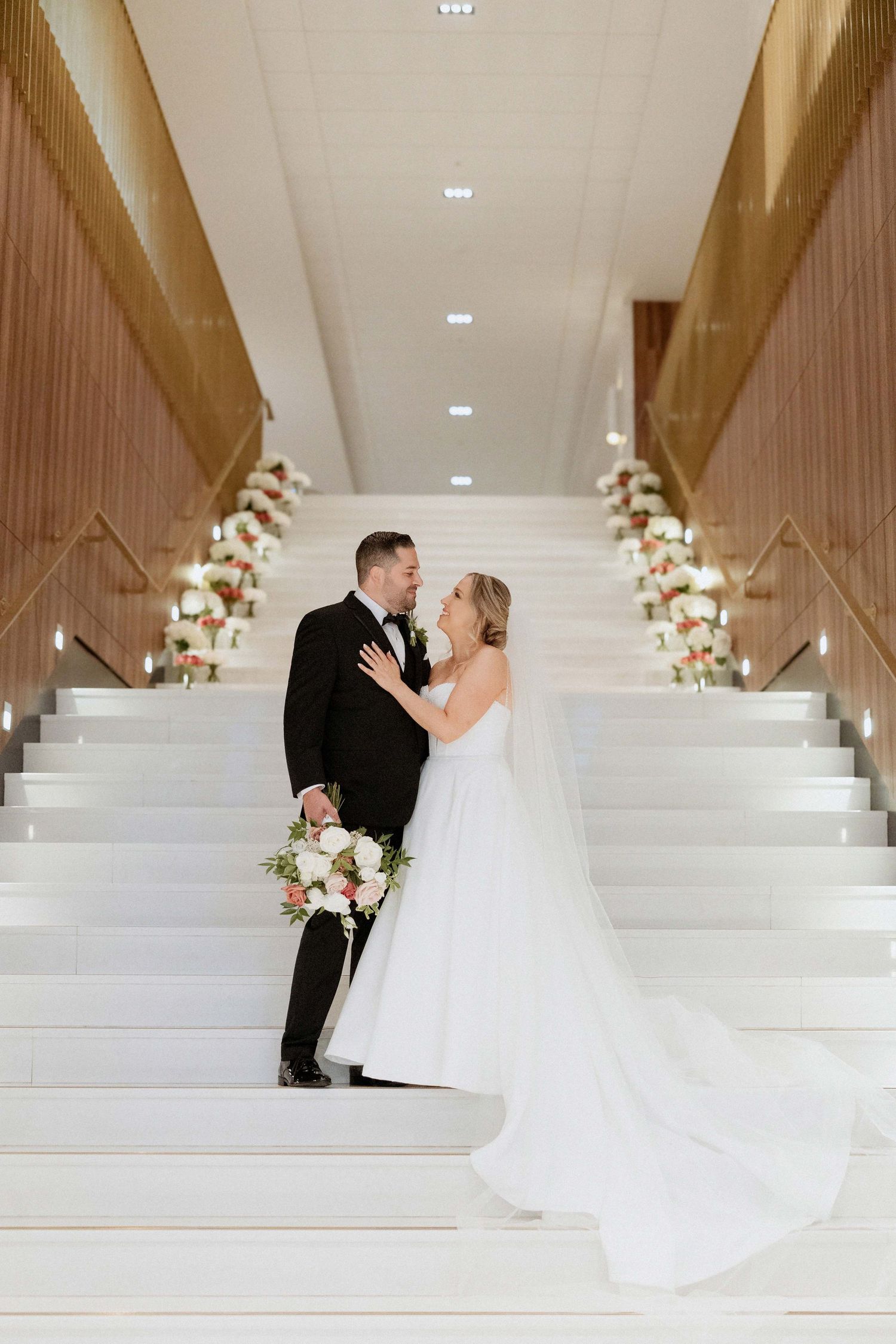 Elegant white wedding venue with modern architectural steps decorated with floral arrangements.