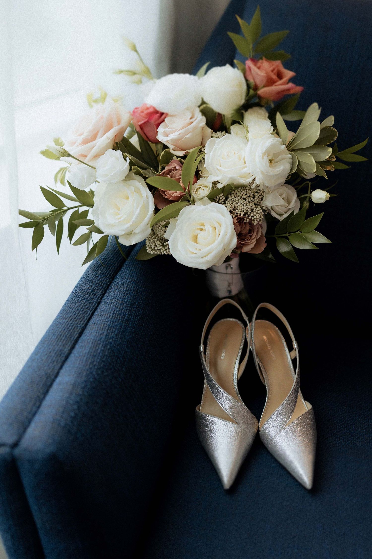 Wedding details featuring silver heels and a romantic bouquet with white roses and pink accents.