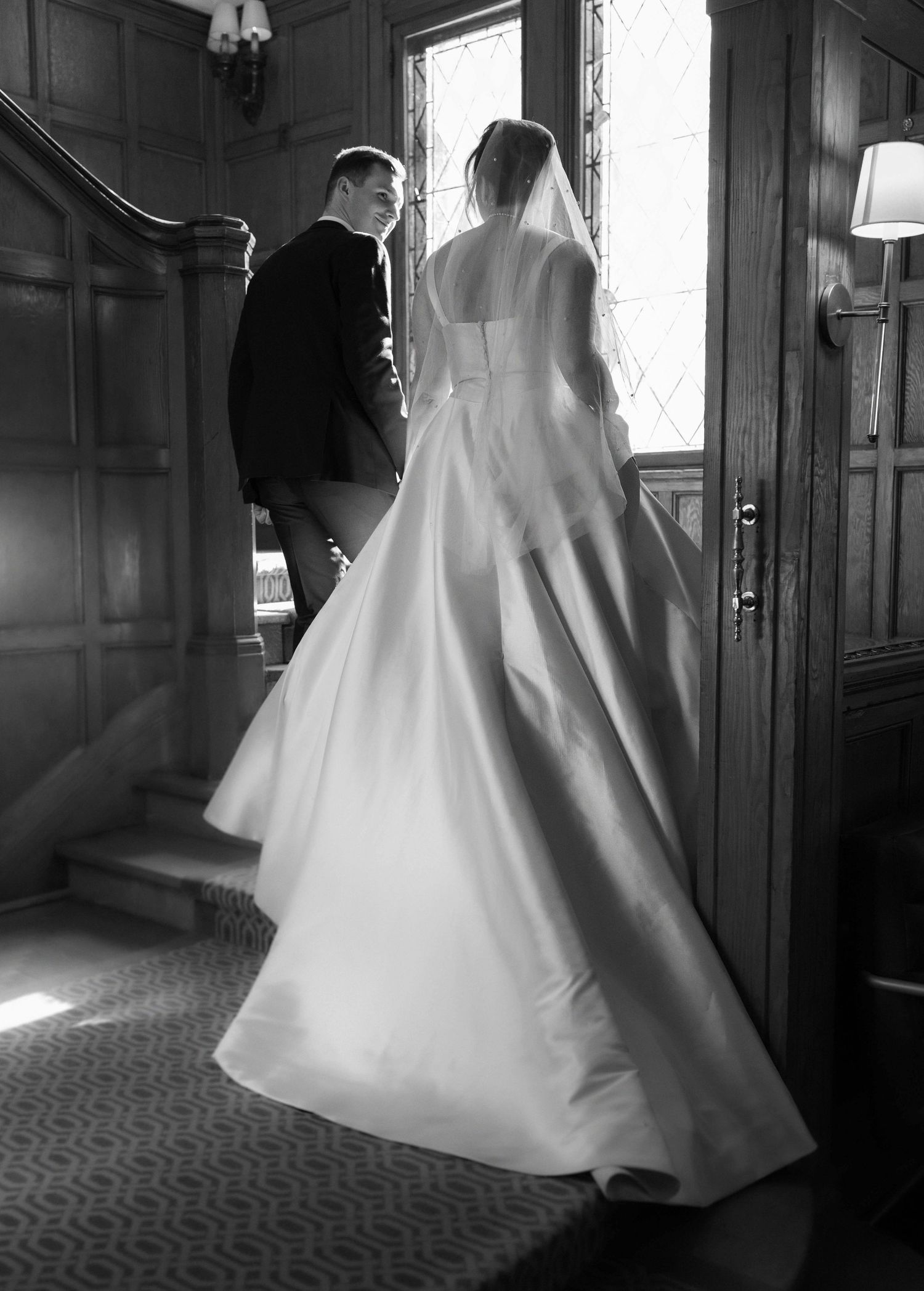 A bride in a flowing white wedding gown twirls gracefully in a dimly lit hallway, creating an ethereal silhouette.
