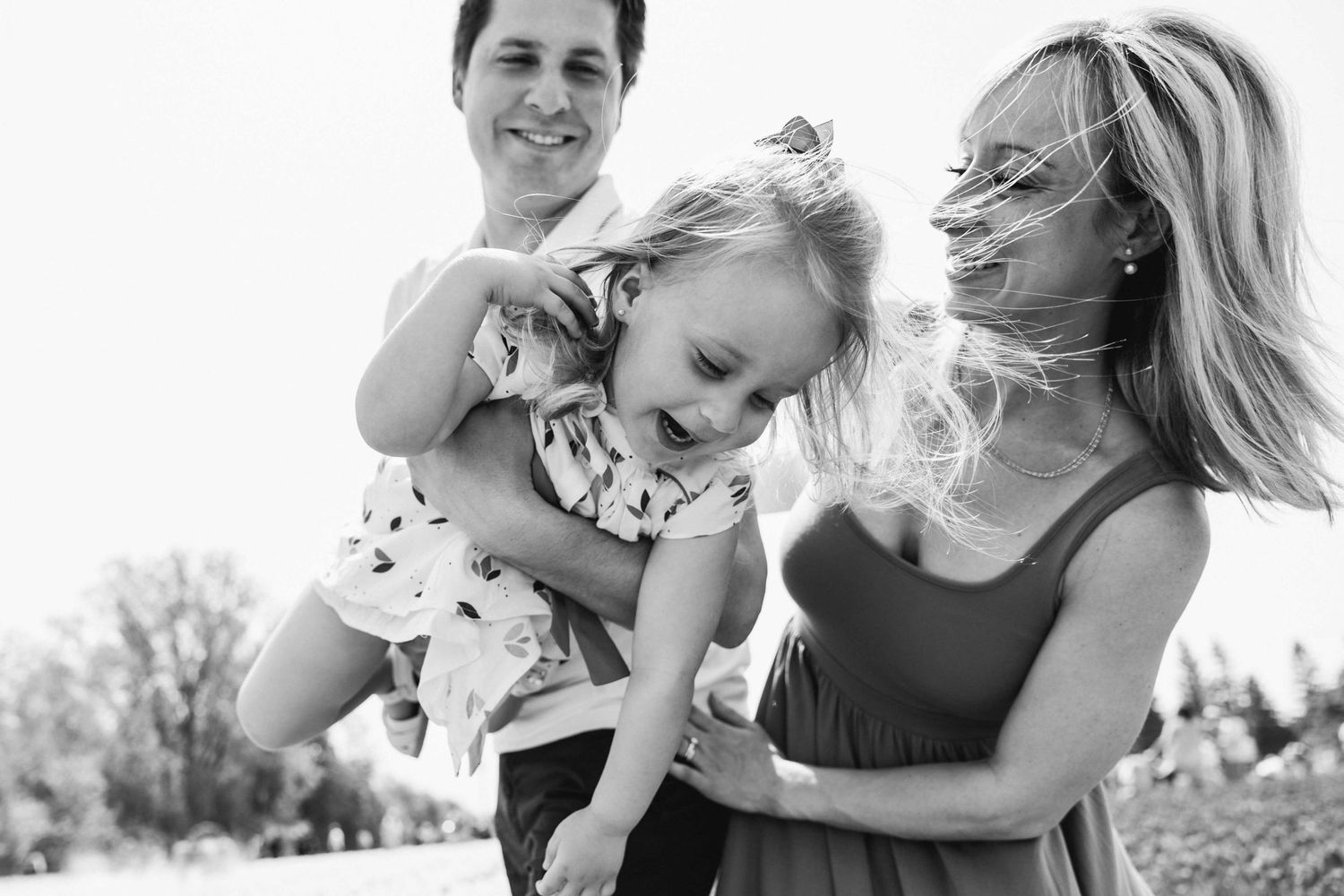 Black and white photo of joyful family moment outdoors in summer.