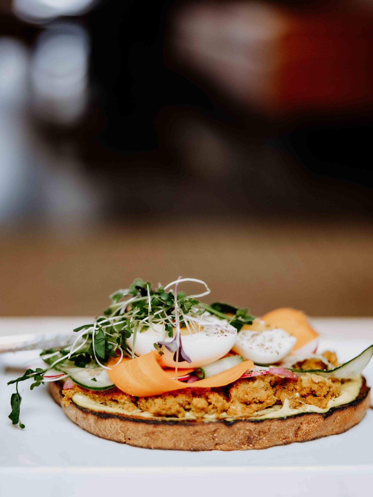 Close-up of gourmet flatbread topped with fresh microgreens and sliced ingredients.