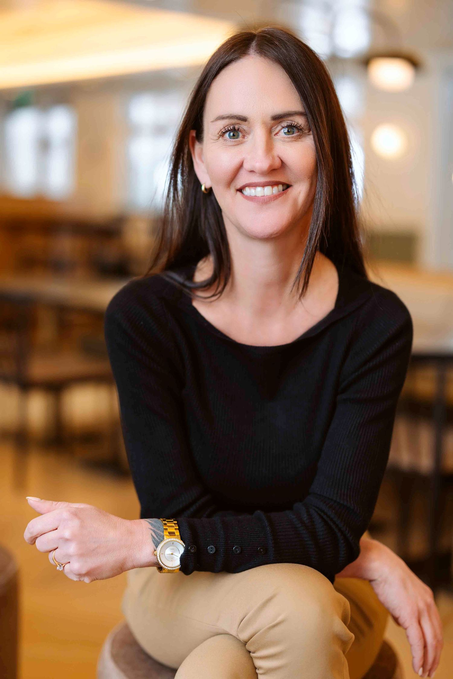 Business casual portraits in black top and khaki pants with office setting background.