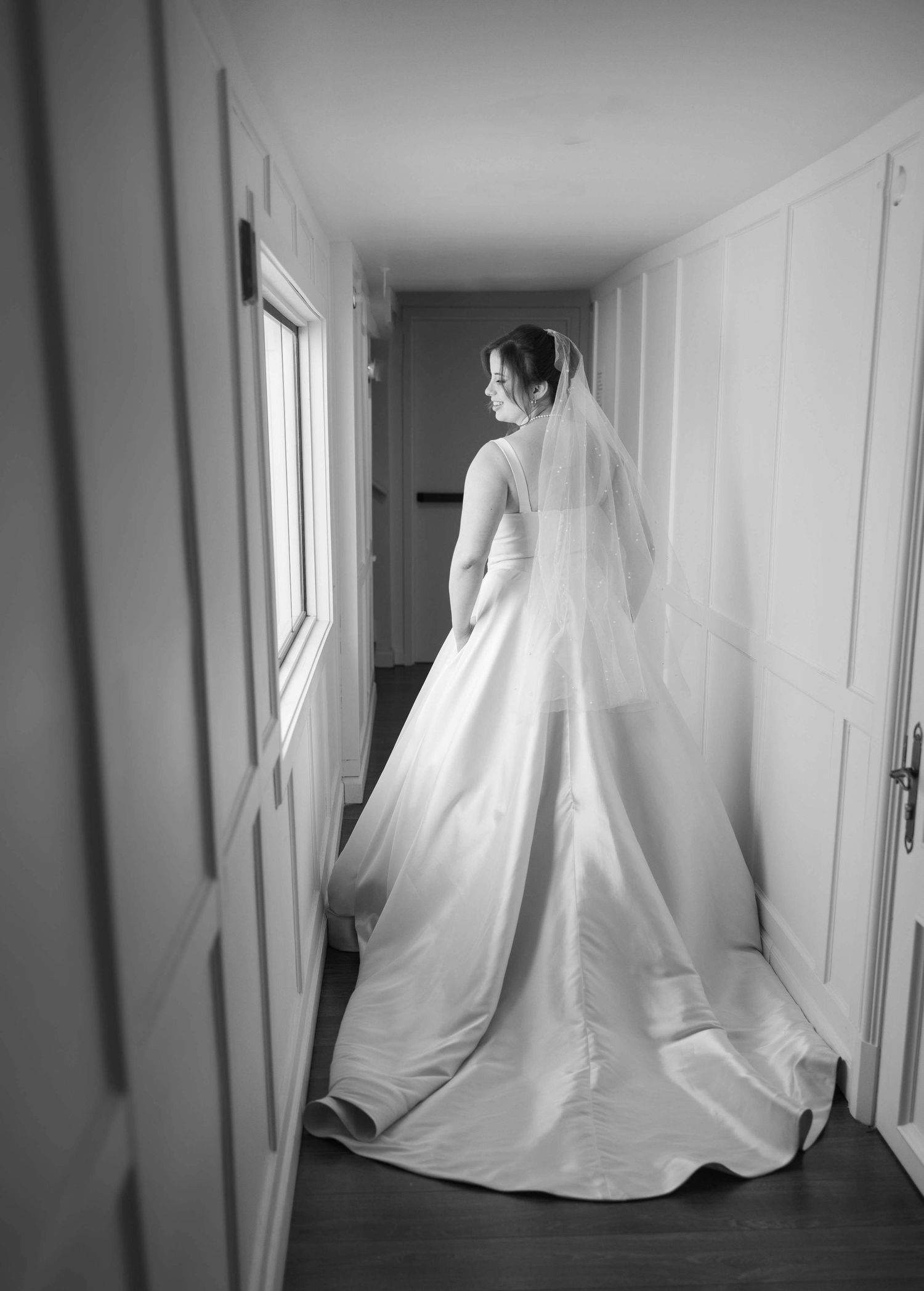 A ghostly figure in white fabric moves through a minimalist hallway in a haunting black and white photo series.