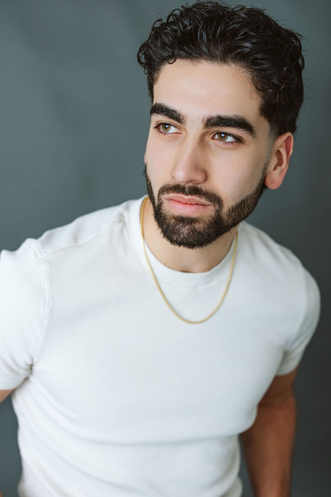 Studio portraits of person in white t-shirt against dark background showing different angles.