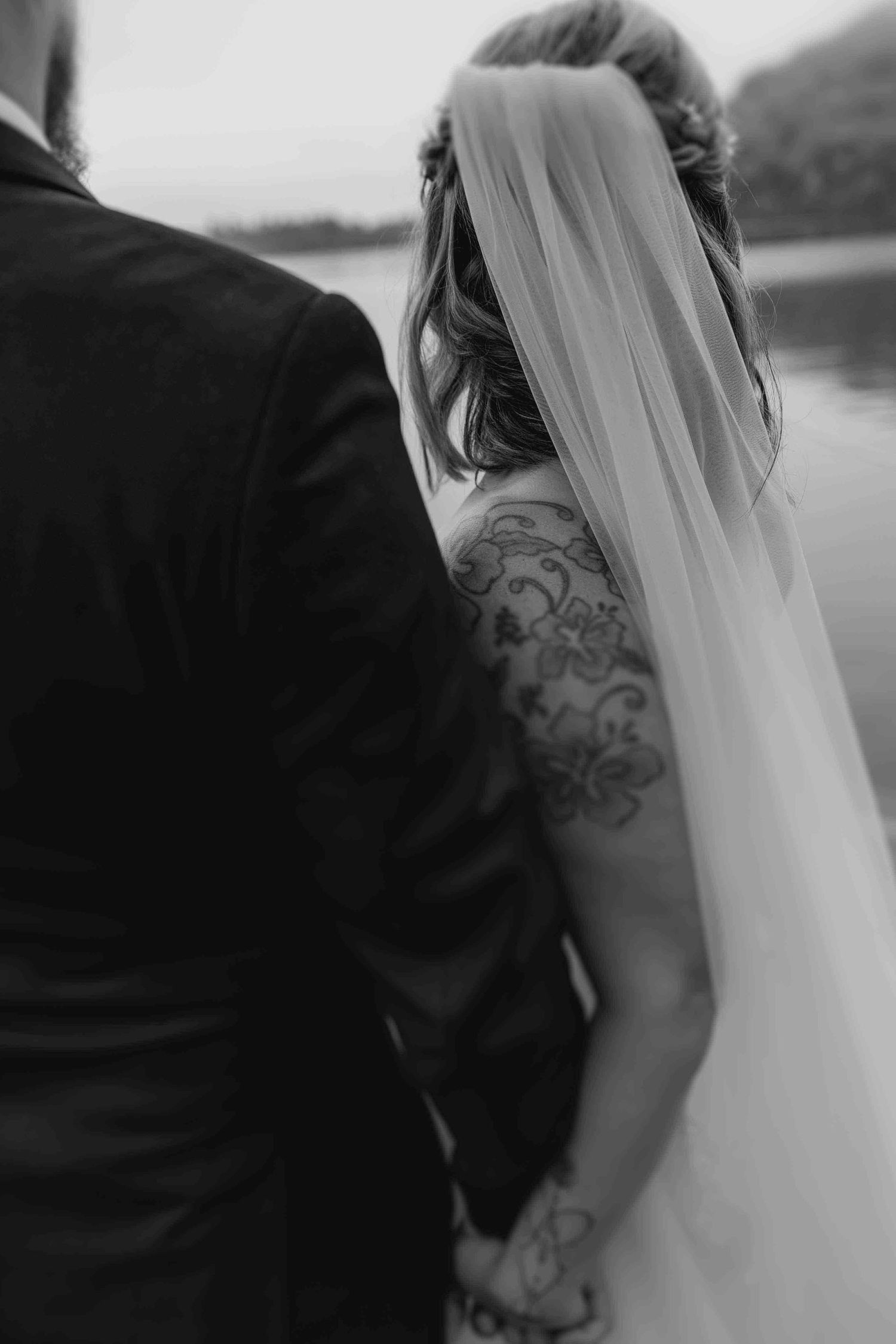 Black and white wedding portrait showcasing intricate lace details and flowing veil.