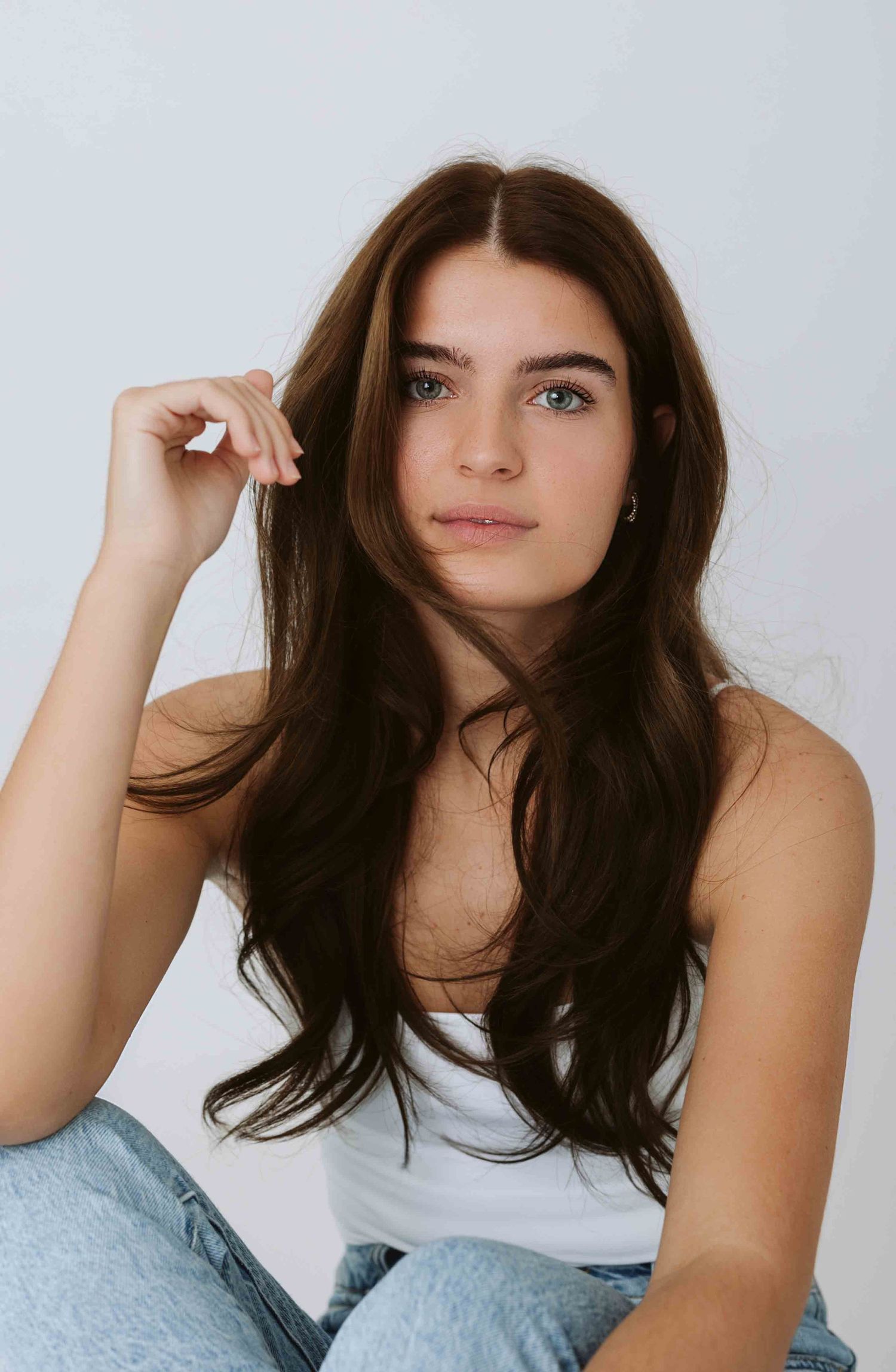 Studio portraits showing casual poses in a white tank top against light background.
