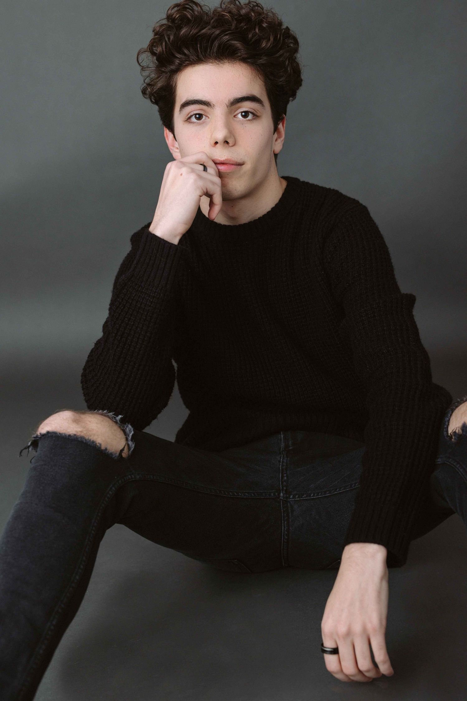 Moody portrait of person in black sweater against grey background. photographe montreal, photographe laval,