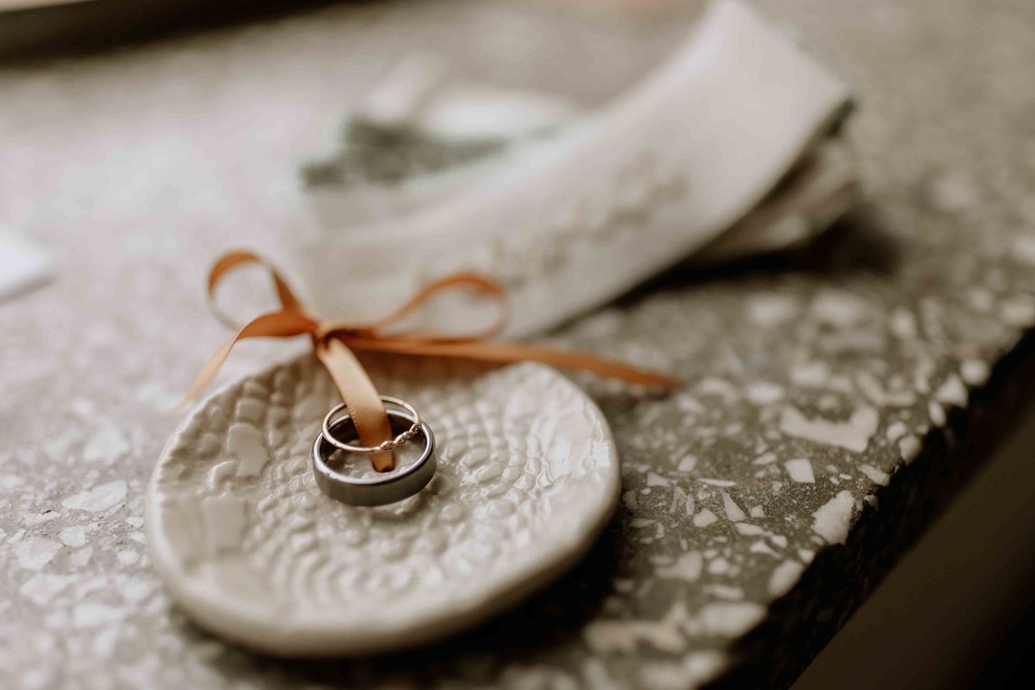 Wedding rings and details photographed on textured lace surface in sepia tones.