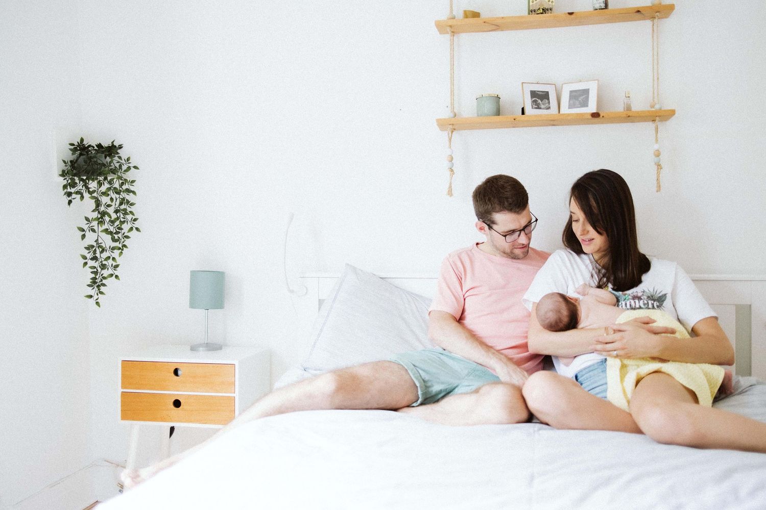 Lifestyle newborn session in bright minimalist nursery with wooden shelving.