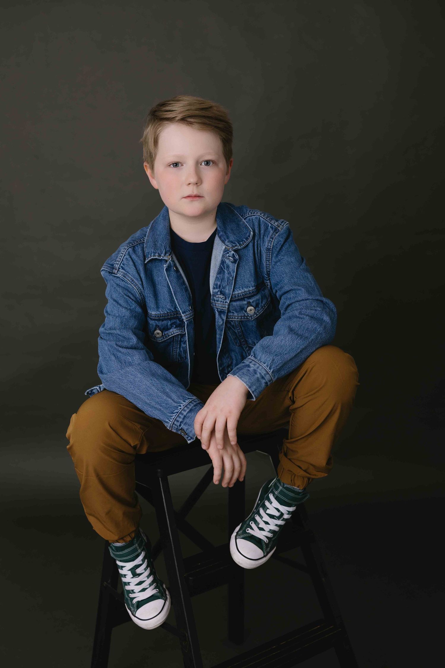 Studio portrait series of young person in denim jacket and brown pants with classic sneakers.