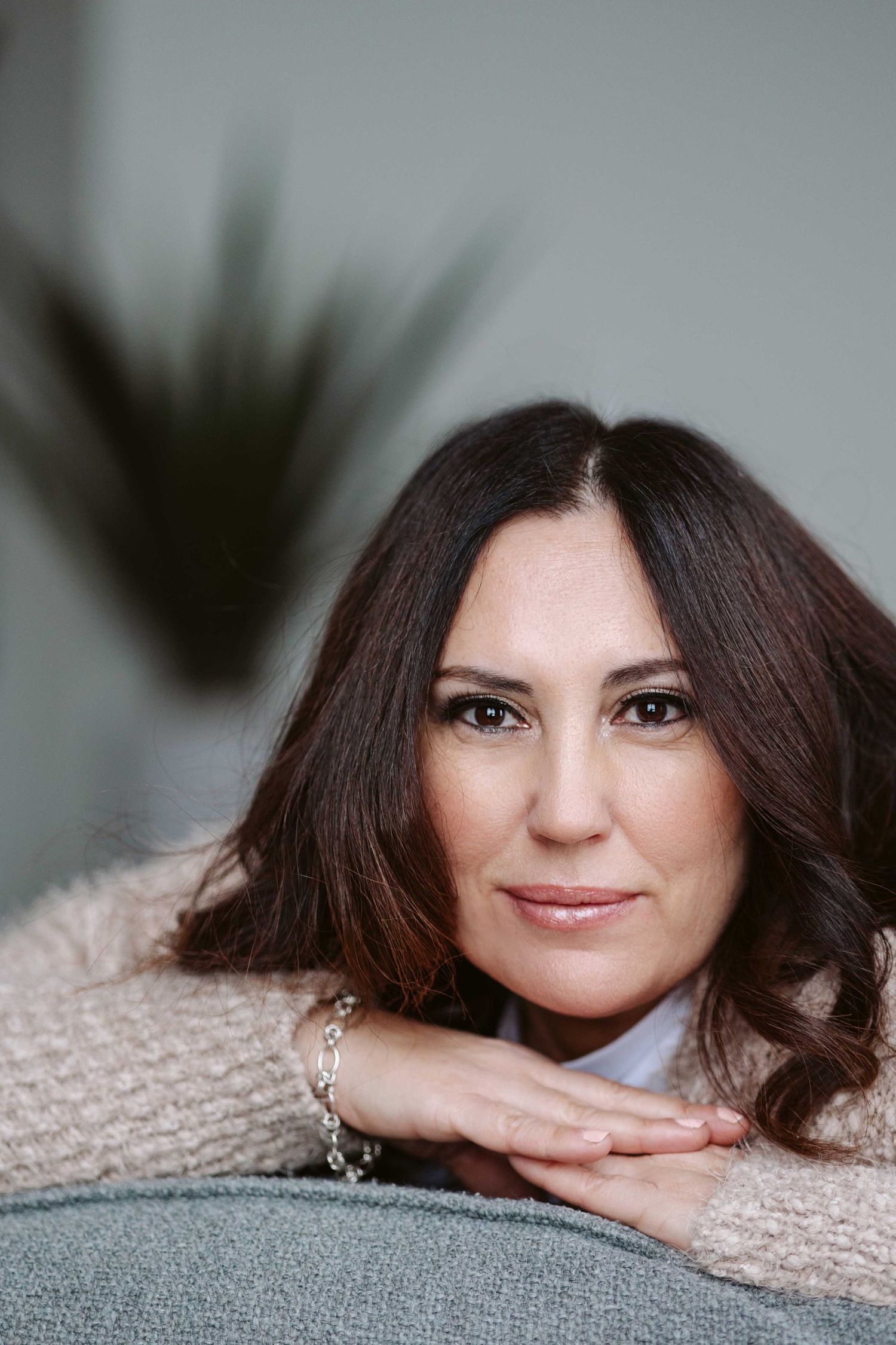 Professional portrait series showing relaxed poses against a light background with dark hair and soft lighting.