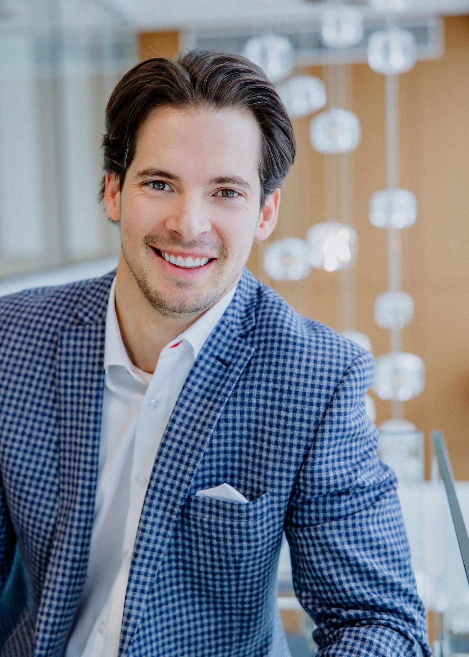 Professional headshots of person in blue checkered blazer in bright office setting.
