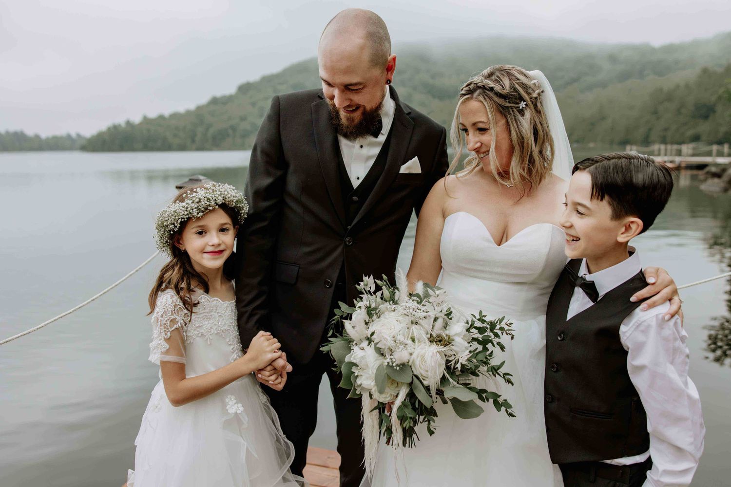Wedding couple and guests celebrate on a scenic lakeside dock during a summer celebration.